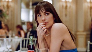 Dakota Johnson sits at a table with a look of mild upset in Materialists.