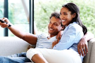 Happy young couple relaxing at home watching television