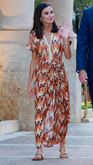 Queen Letizia waves as she walks by the Marivent Palace