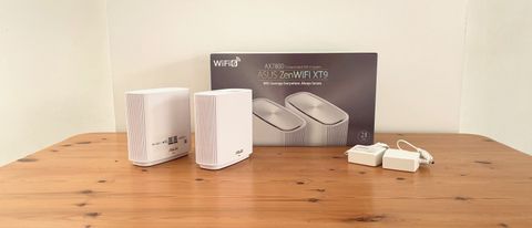 Asus ZenWifi XT9 product review images on a wooden desk