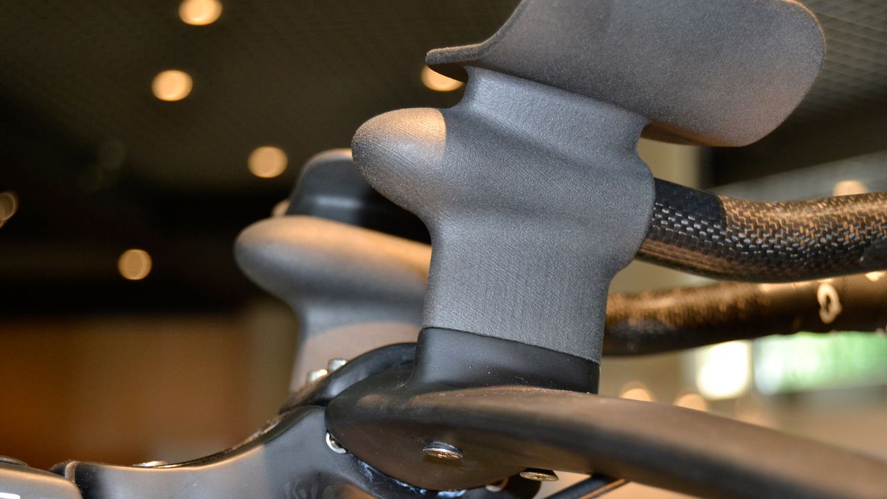 This is 'grown carbon'. It isn't made by Dassi but for now the brand has exclusive access to the technology from its UK inventor for bike parts. It's made in a process that's a little like 3D printing. It begins with a pile of carbon particle dust and ends up with any shape of object you like. Dassi showed us a grown carbon bottle cage, a seat clamp and, most astonishinly because of the loads going through them, these TT risers and extension mounts. This tech makes it possible to completely personalise the object, so you could have one-piece risers at your perfect height and angle. If production can be scaled up it could be a real game changer.