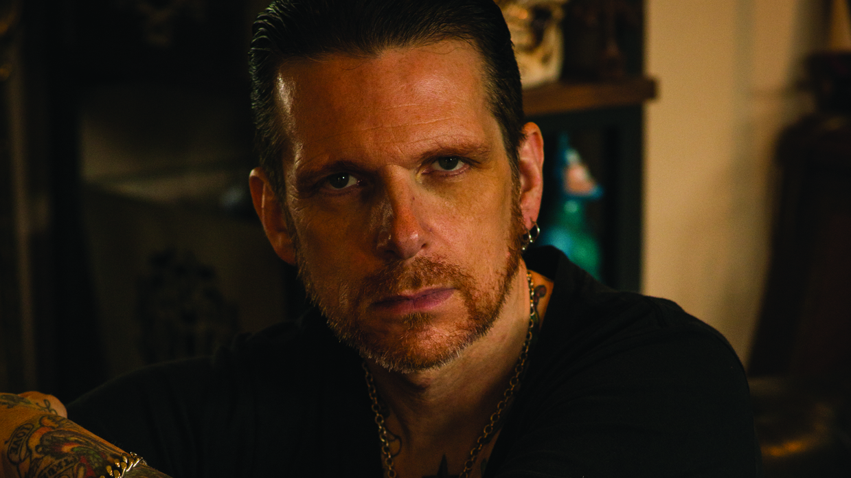 Ricky Warwick, sitting down, staring at the camera.