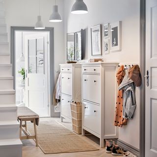 White colored hallway with white cabinets and wall frames with clothing hanging on a clothing knob
