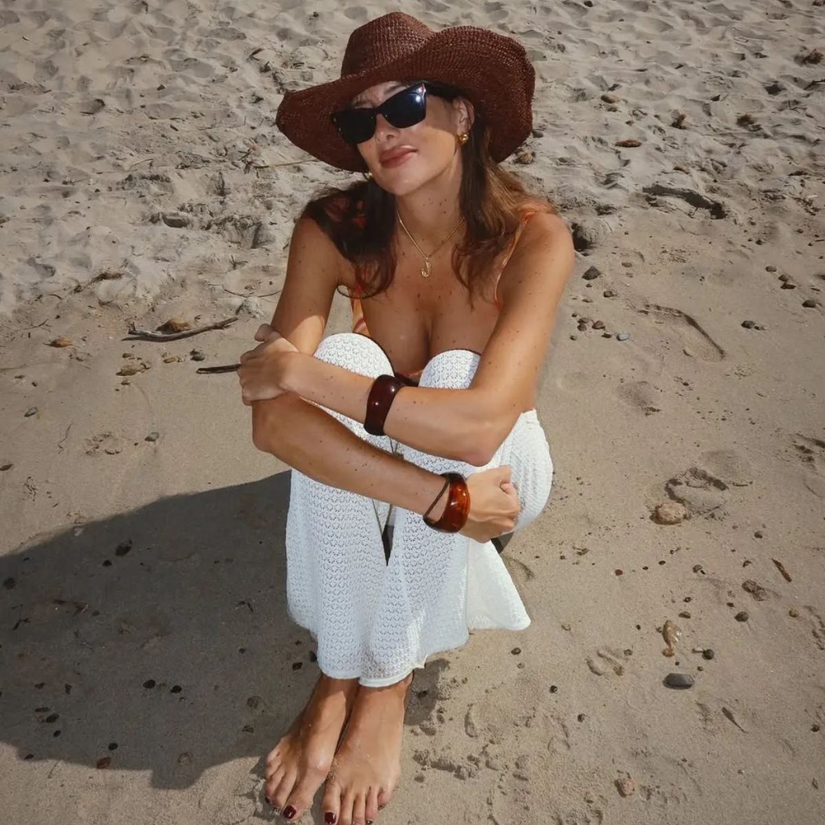 Creator @juliesfi sitting on the beach with a chocolate brown pedicure