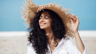 A woman on the beach with protected skin, to illustrate how to reapply sunscreen