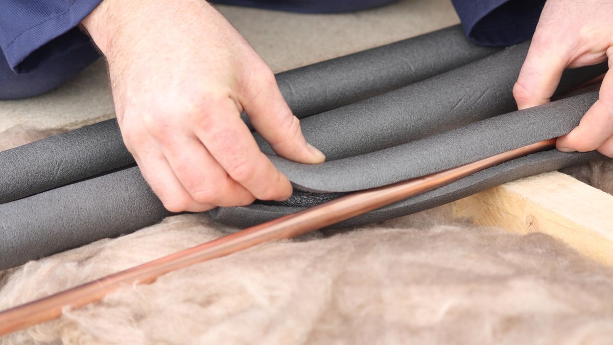 person fitting foam insulation to pipes