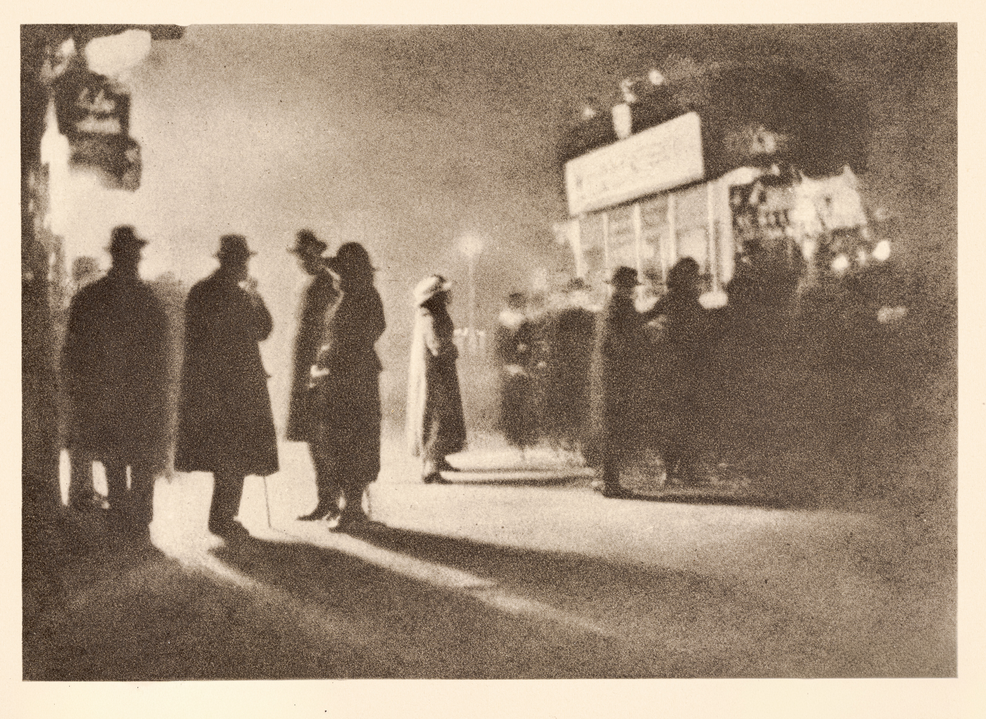 A grainy photogravure of several coated, hatted figures standing in silhouette on a pavement, their long shadows stretching across the ground beneath a glowing street sign.