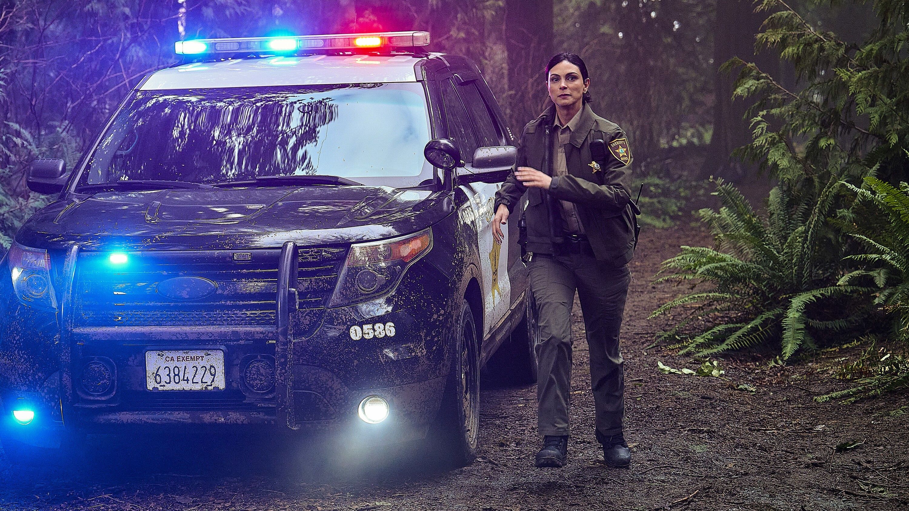 Morena Baccarin as Sheriff Mickey Fox by a squad car in Sheriff Country