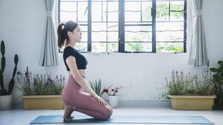 A woman kneeling on the floor indoors with her feet flexed