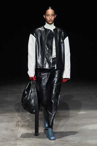Woman on runway in motorcyle jacket and trousers by Jil Sander
