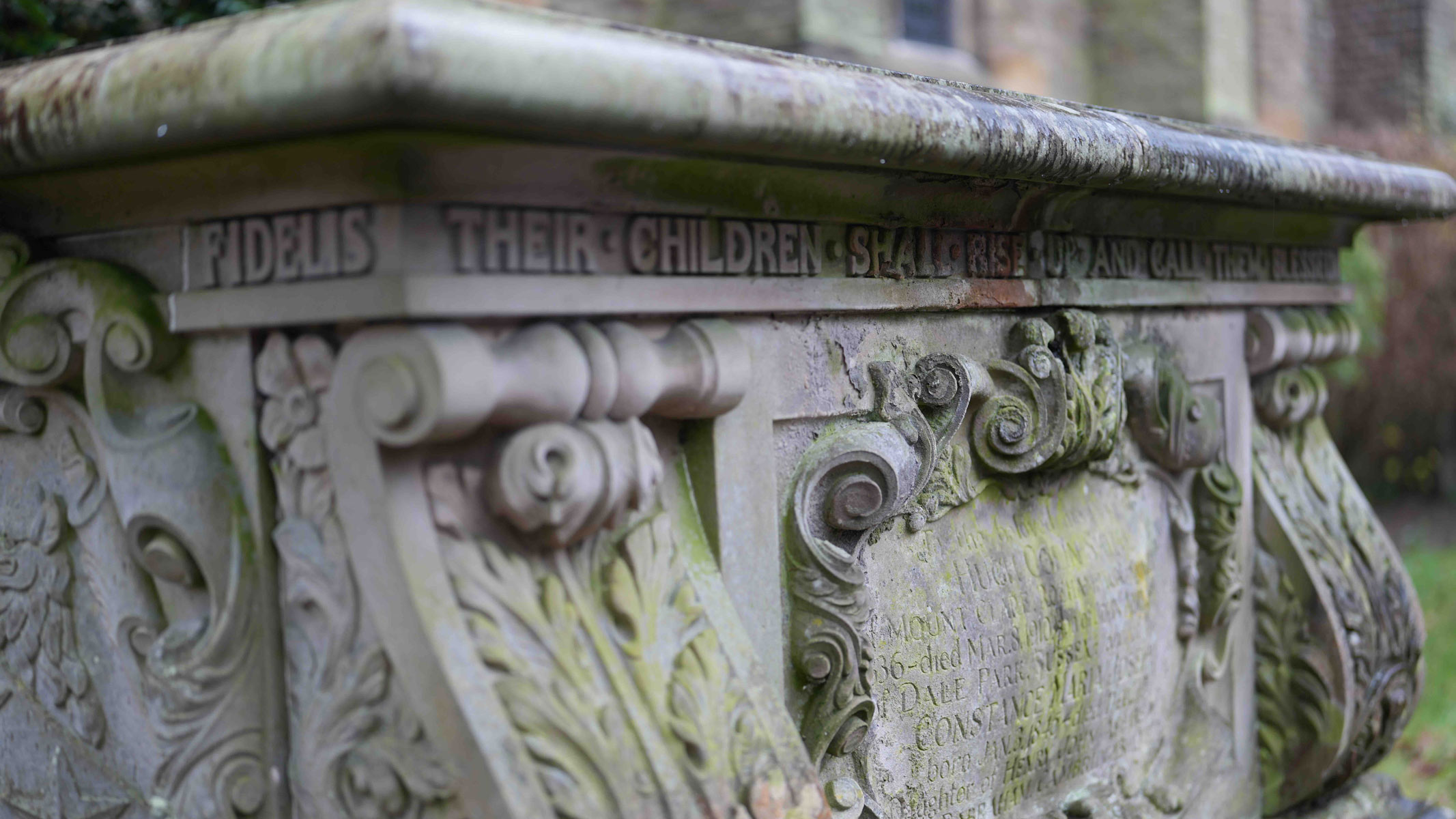 A gravestone with writing and ornate decoration.