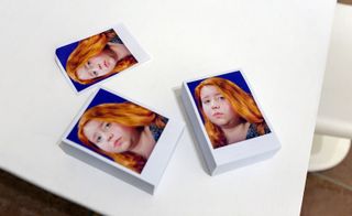Three identical photographs of a woman with red hair on a table.