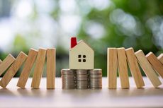 A house figurine standing on a stack of quarters, surrounded by wooden blocks.