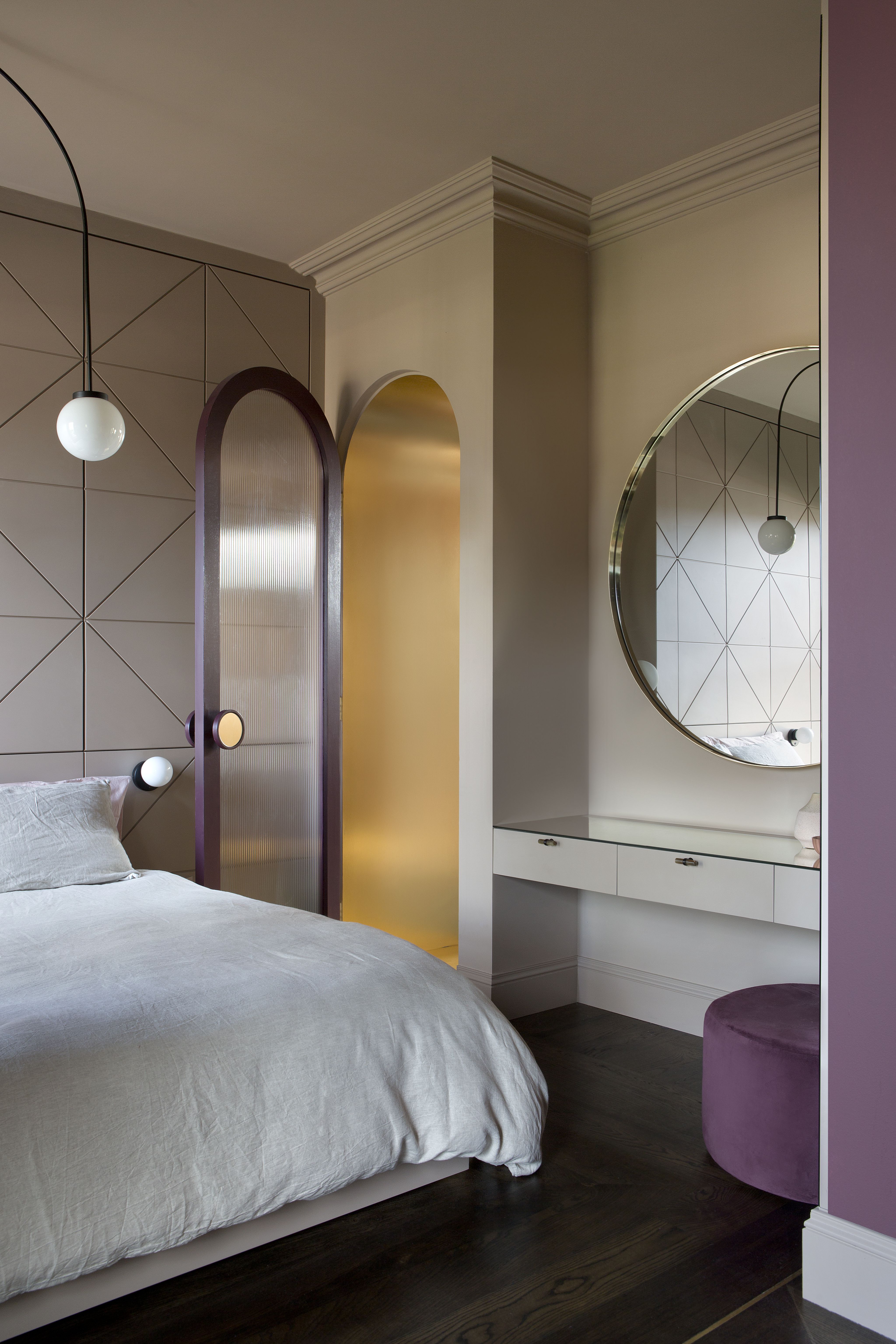 A purple bedroom with a small vanity unit by the bedside