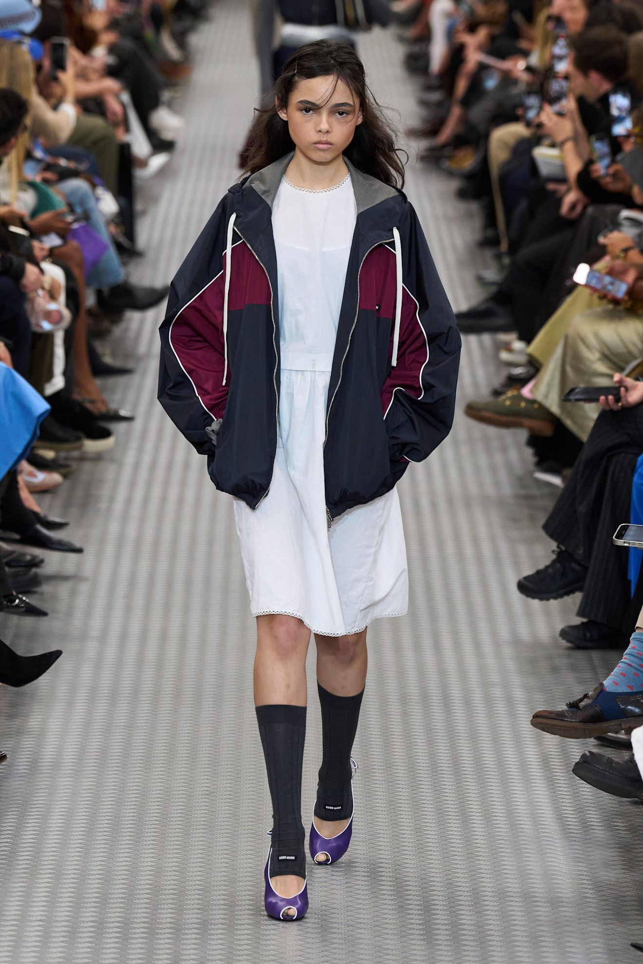 Woman in track jacket and white dress.
