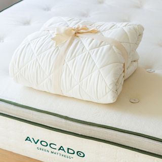 Avocado Organic Mattress Protector tied with a bow on the corner of an Avocado mattress.