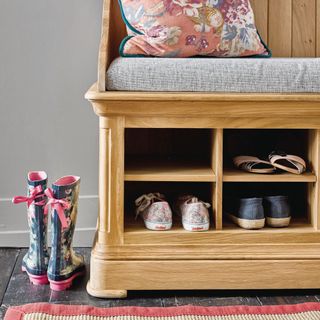 Hallway storage bench with shoes and a seated cushion and a floral pillow