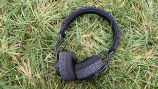 Bästa träningshörlurar för olika sporter: Ett par svarta och grå adidas rpt-01-hörlurar ligger på en gräsmatta utomhus.