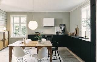 A bright, light kitchen diner with dark kitchen countertops