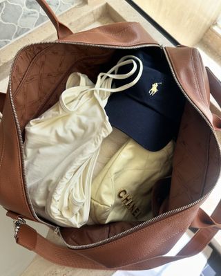 a leather Longchamp duffel bag and black Away suitcase at the airport