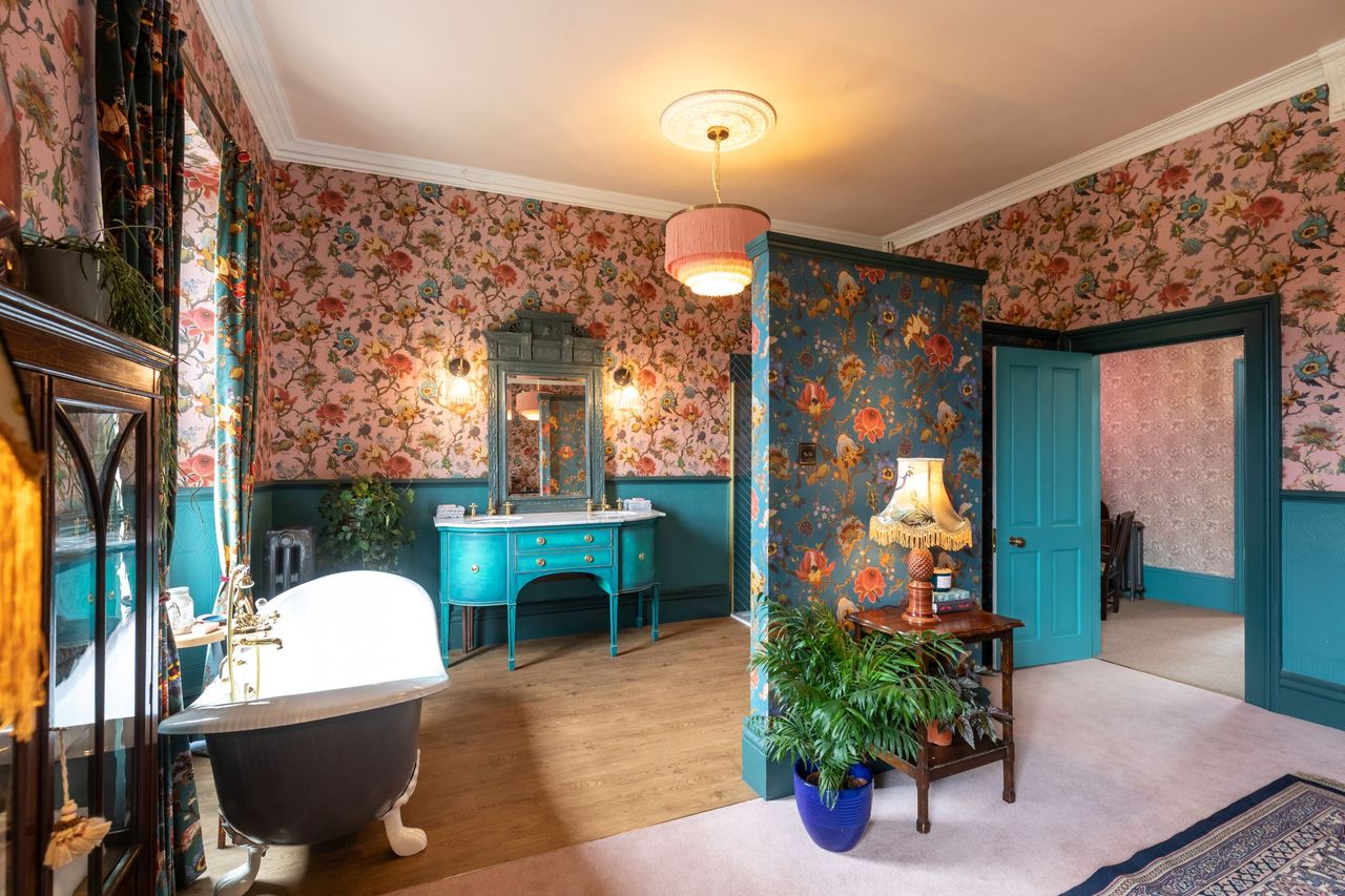 The bathroom flooring is wooden with blue curved top baths and blue dressing table