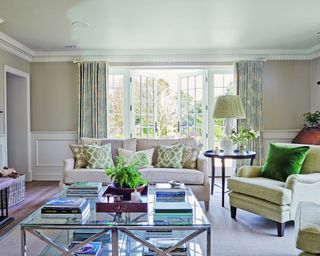 neutral living room with green accents, green cushions, green patterned cushions and blue patterned curtains
