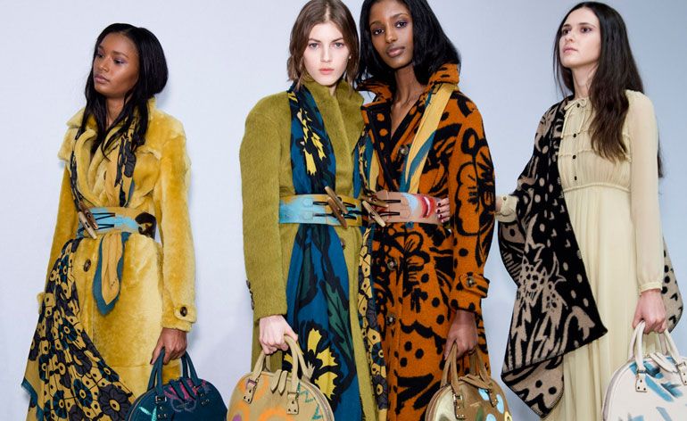 Four women wearing brightly-coloured clothing with bold patterns