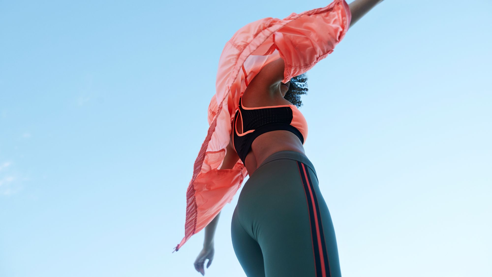 How to run a mile without stopping: A woman running in leggings and a pink raincoat