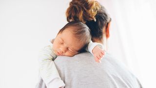 newborn baby being held over woman's shoulder