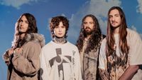 Polyphia photographed in front of a blue sky background.