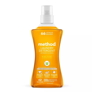 A container of orange Method laundry detergent in ginger mango scent