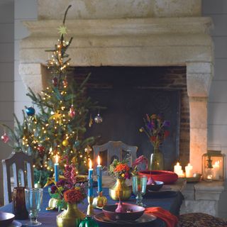 Real Christmas tree in dining room next to fireplace