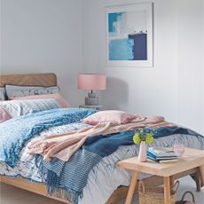 Guest bedroom with bed layered in blue and pink blankets