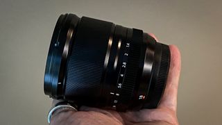 Fujinon XF18mm F1.4 R LM WR being held in reviewer's hand indoors