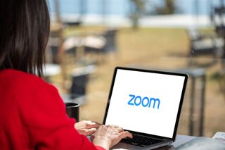 A woman using a laptop with the Zoom logo on the display