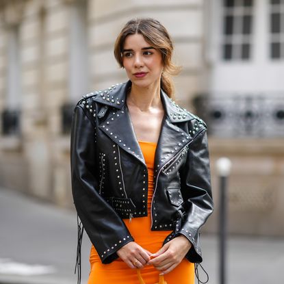 best long lasting lipsticks - Ketevan Giorgadze wears a black shiny leather nailed / studded biker jacket, a gold necklace, a neon orange shoulder-off midi tube dress,