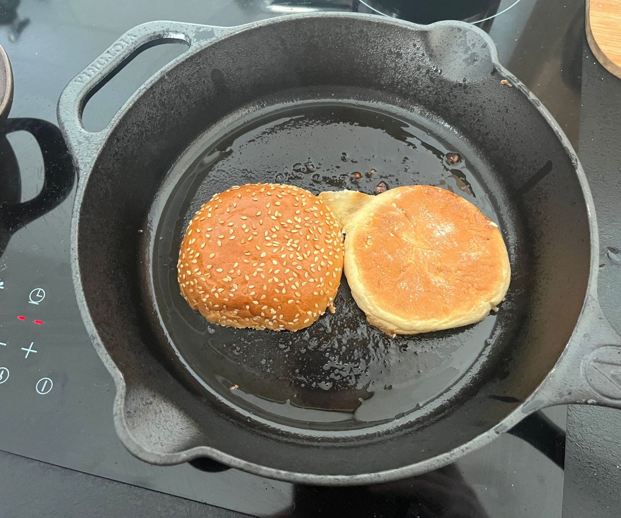A small black cast-iron skillet with a seeded brioche bun inside
