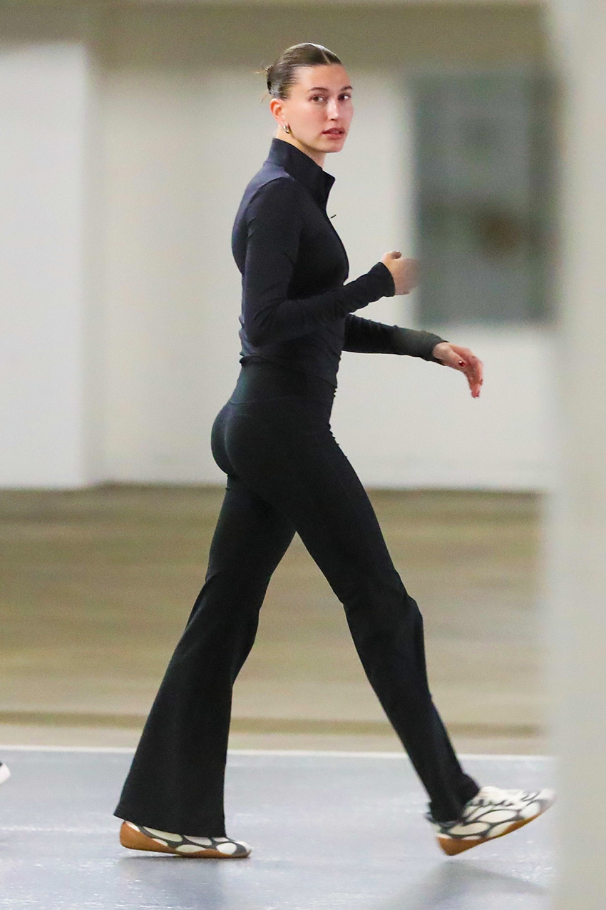 Hailey Bieber wearing a mock-neck jacket, flared Alo leggings, and two-tone sneakers