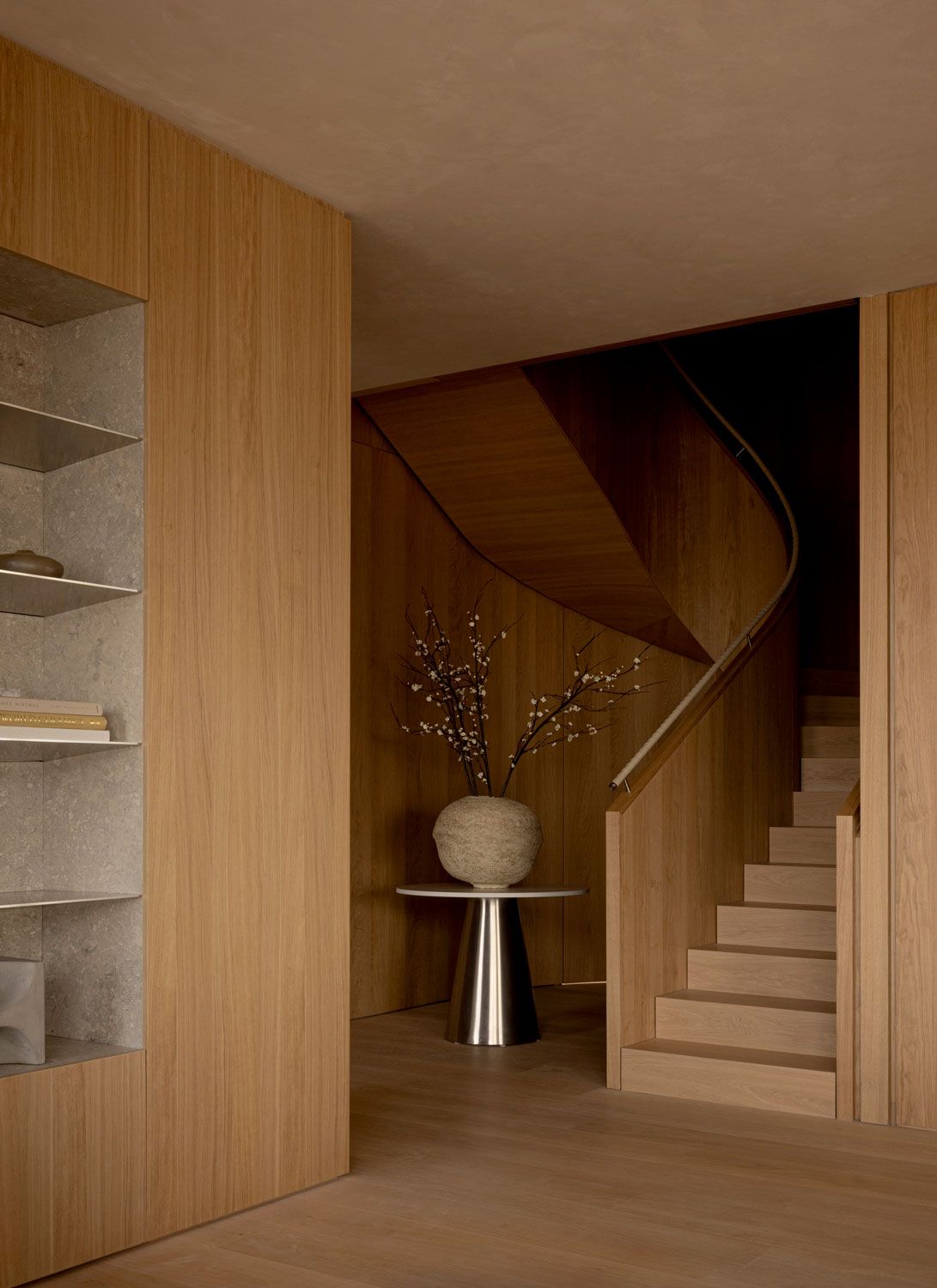 Oak-clad staircase inside 262 Fifth Avenue by Norm Architects, with curved timber detailing, built-in shelving, and a sculptural side table