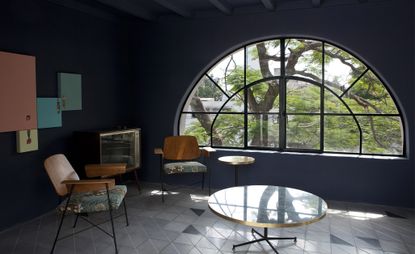 Casa Fayette lounge with large arch window, navy blue walls and grey floor tiles