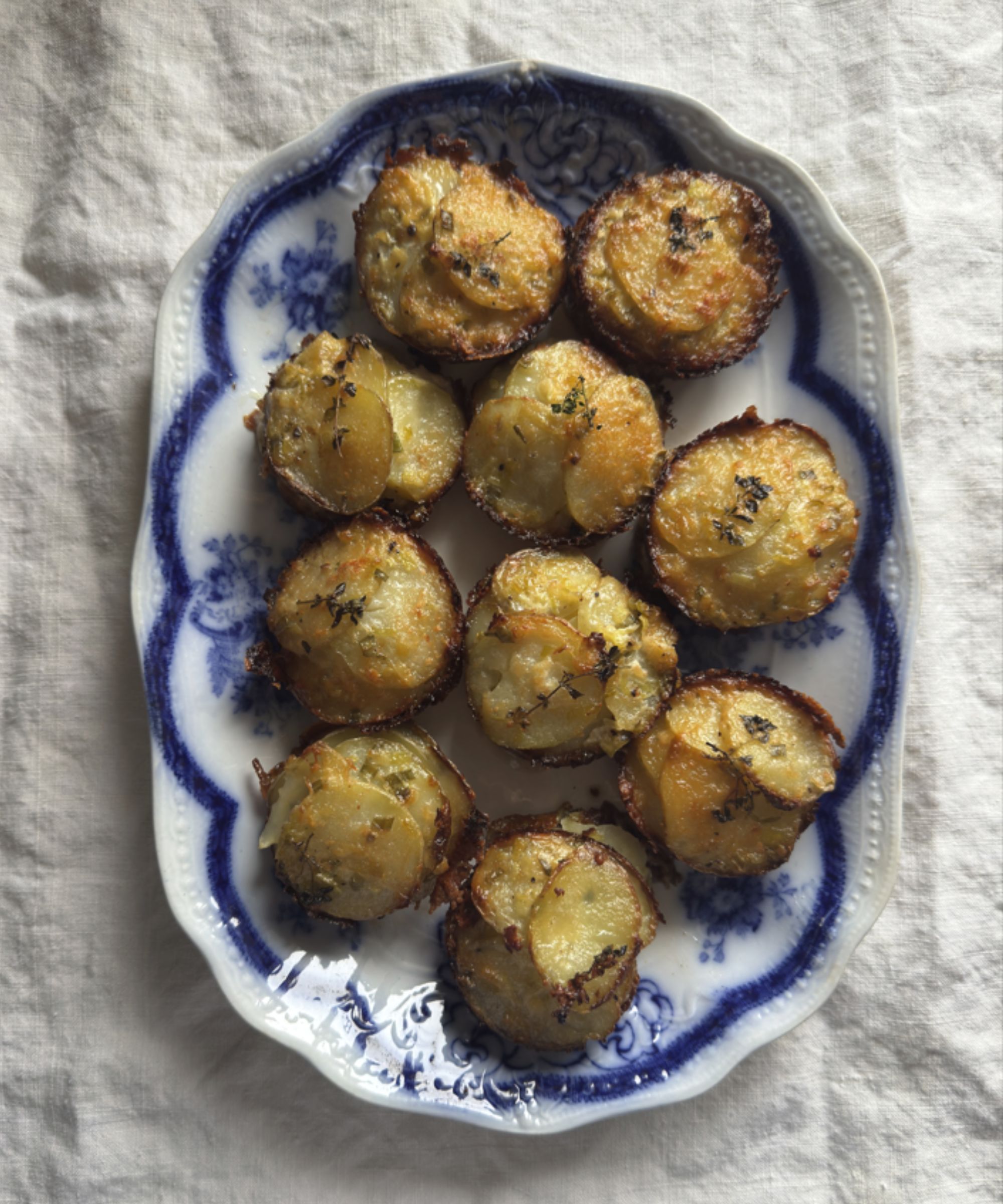 Mini potato gratins on a blue and white plate and white tablecloth
