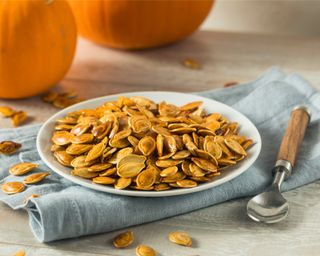 Roasted pumpkin seeds on a plate with a spoon