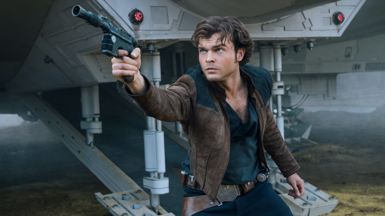 Alden Ehrenreich sosteniendo un bláster como Han Solo