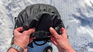 Closing the roll-top opening of the Db Fjäll 34L Backpack