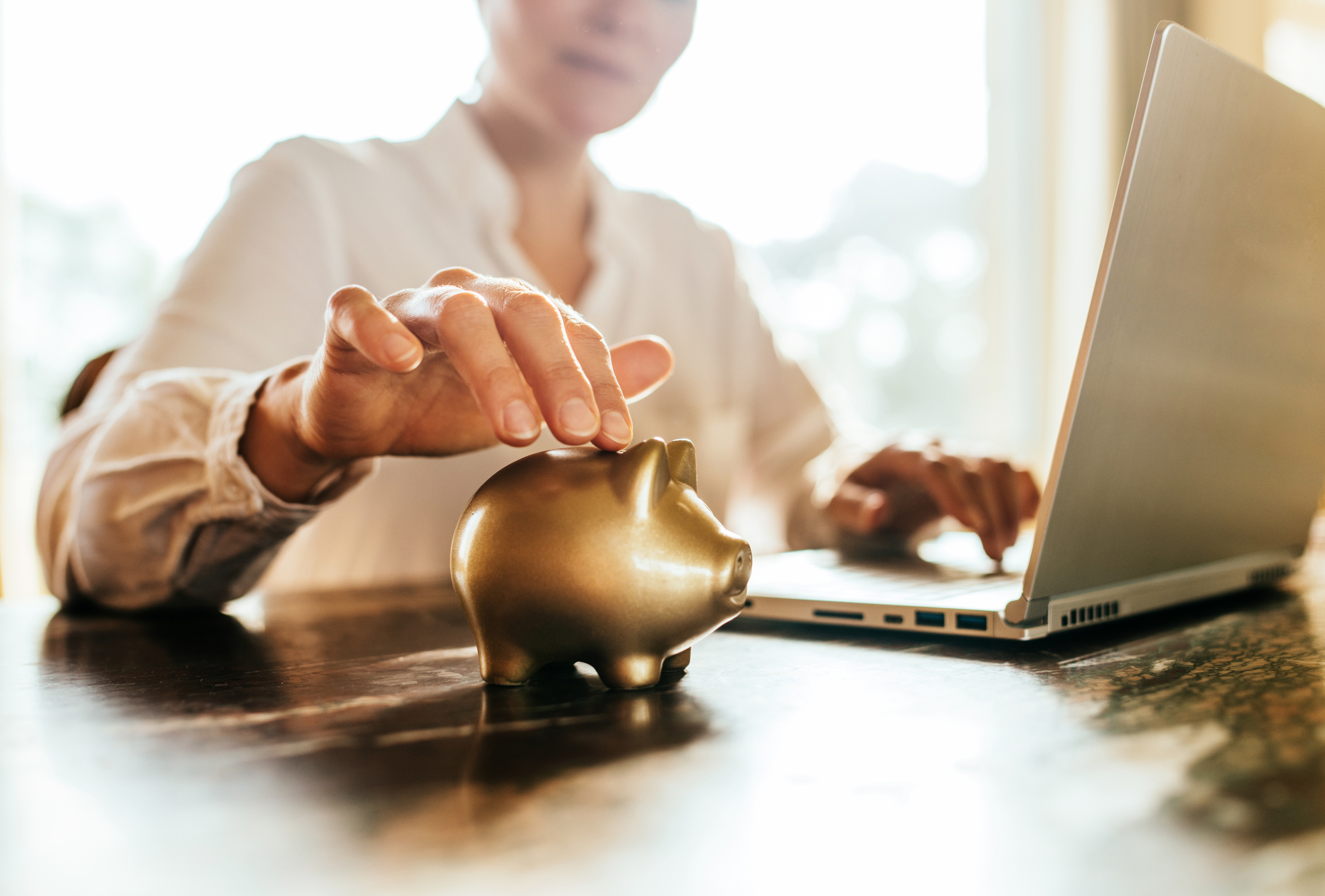 a woman depositing coins into a gold piggy bank