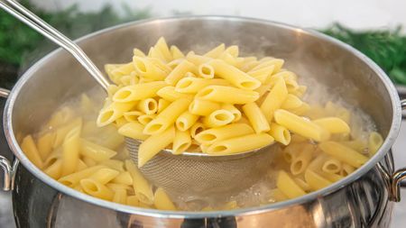 Cooking pasta in water and using a sieve to drain the water