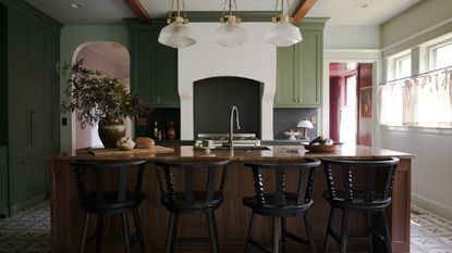 A Craftsman kitchen with dark green cabinets, light green walls, and a wooden island