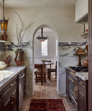 Drew Michael Scott's kitchen featuring brown cabinets, marble backsplashes and limewash walls