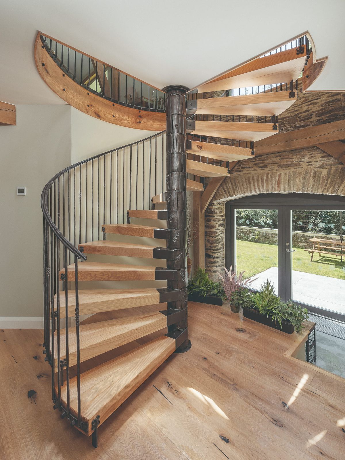 An iron and wood spiral staircase inside a modern barn conversion