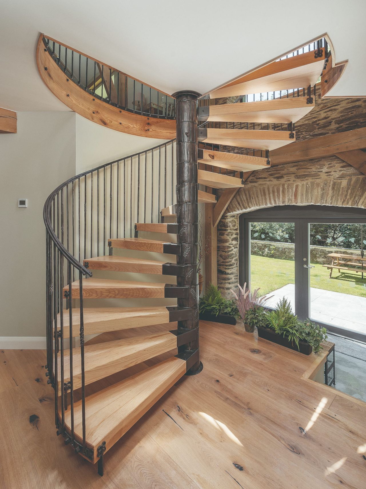 An iron and wood spiral staircase inside a modern barn conversion